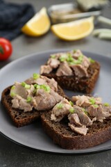 Tasty sandwiches with cod liver and green onion on light grey table