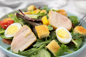 Delicious salad with croutons, chicken and eggs served on table, closeup