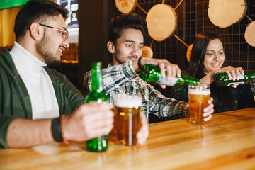 Indian friends celebrating in a pub with beer