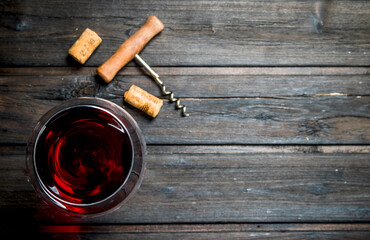 glass of red wine with a corkscrew and corks.