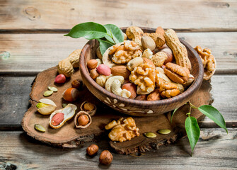 Different kinds of nuts in bowl with leaves.