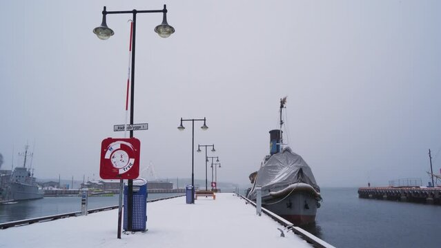Moored Boat With Covered Forward Bow Tied To Snow Covered Pier Dock At Aker Brygge In Winter. Static Shot