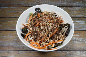 Traditional salad mixed vegetable dressing with almond sliced and crab sticks serving in the bowl. Famous appetizer menu in restaurant. 