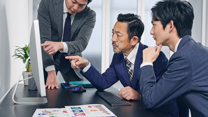 パソコン画面を見ながら会議するビジネスマン