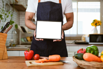 Portrait of asian man making salad and holding tablet at home. cooking food and Lifestyle moment