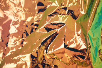 Crumpled iridescent foil with a real texture. Blurry abstract modern holographic background in...
