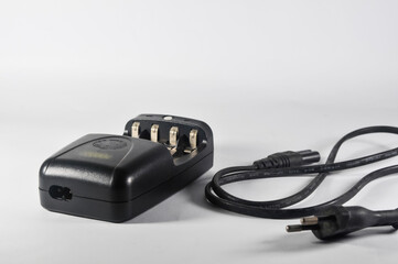 black battery charger and a cable on white background