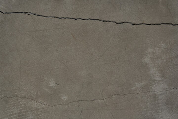 A cracked concrete wall covered with a gray cement texture as a background. Horizontal design with copy space. High quality photo