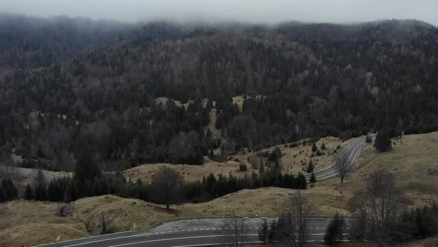 Scenic View Of A Mountain Road With Dense Trees Against Overcast Sky. Aerial Drone Shot