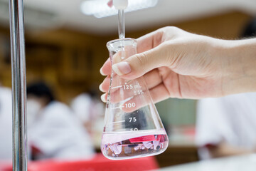 Close up student doing a chemical experiment in laboratory at the elementary school. Education concept.