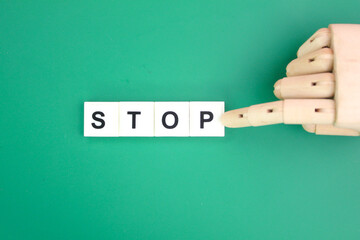 wooden hand pushing letters of the alphabet with the word stop. stop concept. concept cannot be done