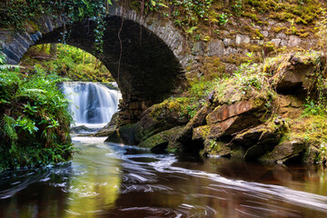 Torc Waterfall flowing under a bridge in Killarney National Park, Ireland