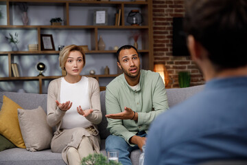 Multiracial quarrel between husband and wife at a session with a psychotherapist. A visit to a family psychologist for a married couple. A doctor consults an unhappy married couple. Help psychologist.