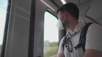 Crowded train at 9 euro ticket in Germany. Male passenger wearing mask stands at door of train and looks through window, no seats in wagon. Care for male health. Smog filter for air purification. 