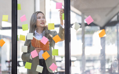 Business female employee with many conflicting priorities arranging sticky notes commenting and...