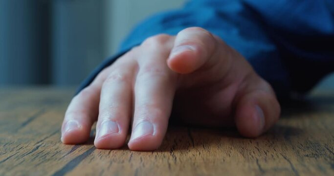 Male waiting for something while fingers tap on the table. Close up male hand nervously tapping finger on the table