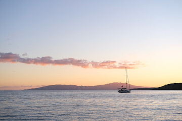 Fototapeta premium Sunset in the sea, silhouette of sailboat on the horizon, sunrise