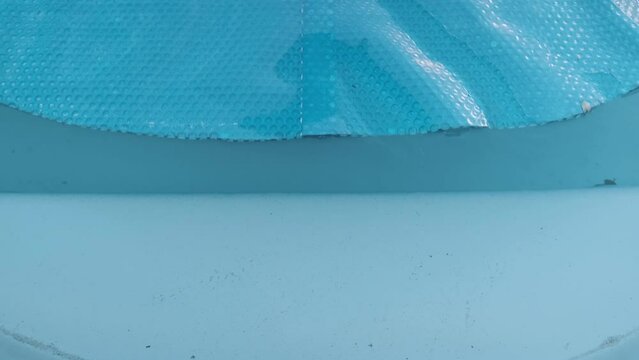 Opening bubble wrap to protect the pool. Home swimming pool protection concept
