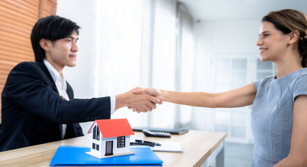 Real estate agent and client shake hands after reaching an agreement on home purchases and insurance.