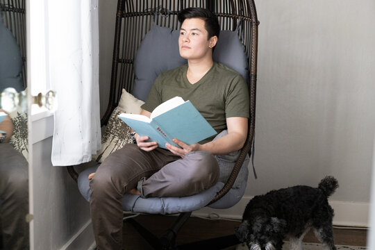 A transgender man reads a book at home