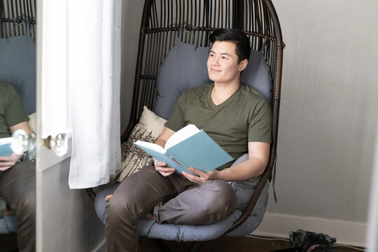 A transgender man reads a book at home