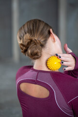 The athlete does a relaxing massage of the neck and back with the help of a prickly rubber ball. 