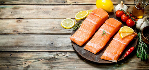 Raw salmon fish filet with lemon, tomatoes and herbs.