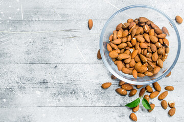 Almonds in a glass bowl with leaves .