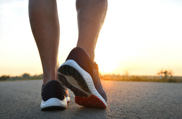 Close-up of running shoes in use with sunrise background.