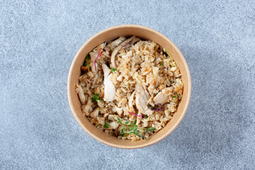 A top down view of a paper to go container featuring a chicken and rice entree.