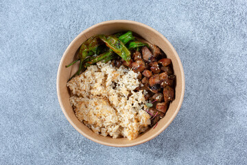A top down view of a paper container featuring Asian BBQ beef and fried rice.