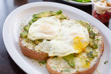 A view of avocado toast, featuring fried eggs.