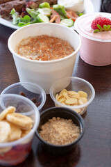 A view of an oatmeal and yogurt brunch meal, featuring condiment cups of toppings.