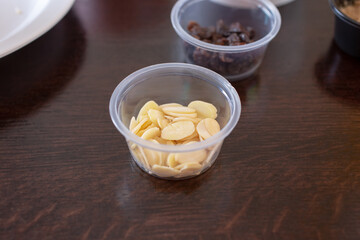 A view of a clear condiment cup of sliced almonds.