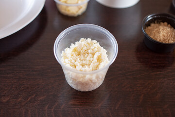 A view of a plastic condiment cup of small crumble cheese.