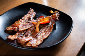 A view of a plate of bacon strips.