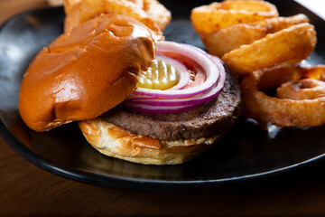 A view of an entree of hamburger and onion rings.
