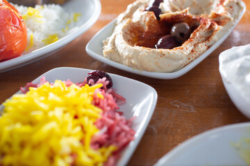 A view of a variety of Mediterranean side dishes such as hummus and cherry rice. 