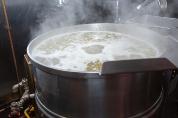 A view of a large steam kettle appliance in a restaurant kitchen.