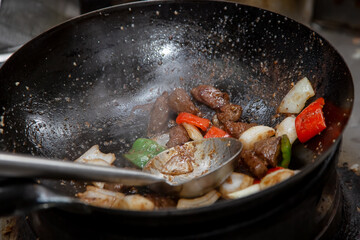 A view of a kitchen wok cooking shaken beef.