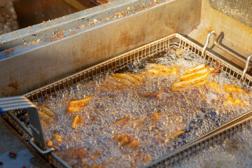 Fototapeta na wymiar A view of an order of waffle fries boiling away in a deep fryer machine.