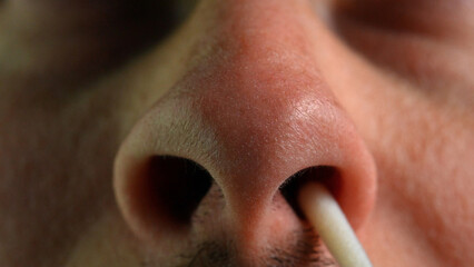 Man performs a covid-19 quick test at home. Introducing nasal stick into the nose to check the...