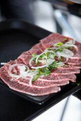 A view of a tray of thin slices of raw American wagyu beef.