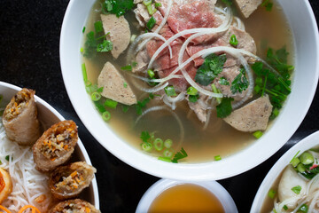 A top down view of a pho combo bowl, among other Vietnamese entrees.
