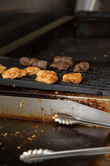 A view of pieces of chicken and beef kabobs cooking on a restaurant kitchen grill.