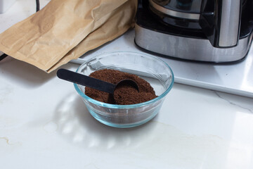 A view of a glass bowl of ground coffee, in a home kitchen lifestyle setting.