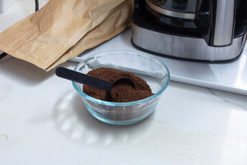 A view of a glass bowl of ground coffee, in a home kitchen lifestyle setting.