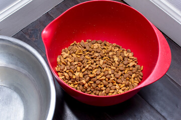 A view of a bowl of dry dog food on the floor.