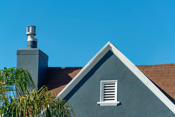 Dark blue stucco house facade or exterior with white accent paint on roof edge and visible chimney...