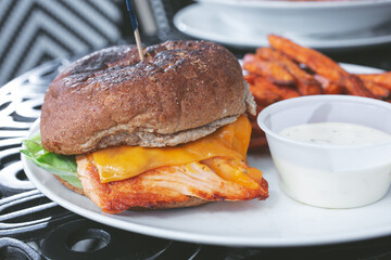 A view of a salmon sandwich, with a side of sweet potato fries.